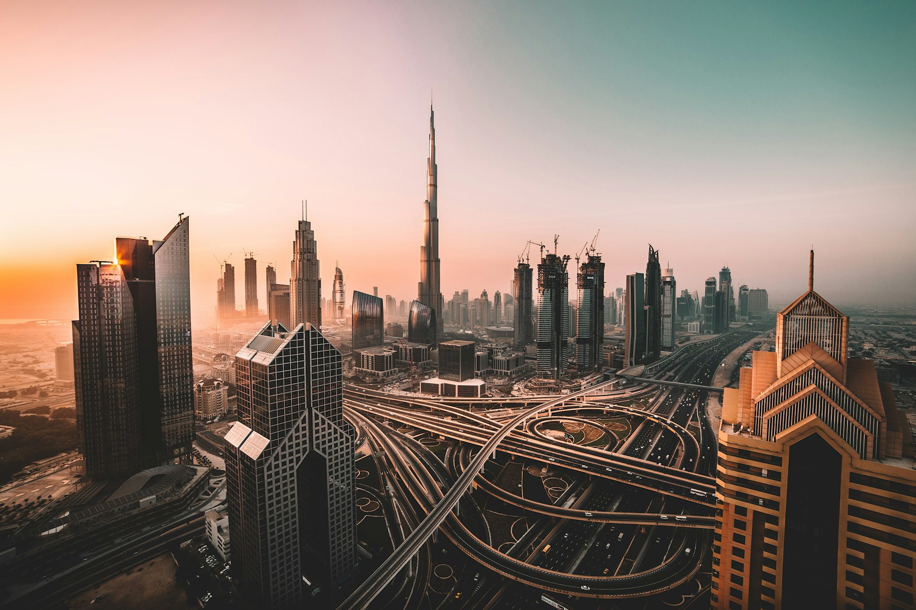 Aerial view of Dubai at sunset, with the Sheikh Zayed Road interchange in the foreground